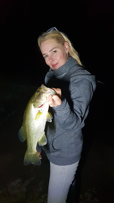Girl holding nice bass caught while fishing at night at Mearns Dam